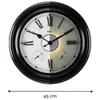 A close-up of a large, round wall clock with Roman numerals and two smaller dials, one on the left and one on the right. The clock face is split vertically, with the left side brightly lit and the right side in shadow with a warm glow emanating from the ce Produktbild-Vorschau