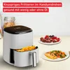 A white air fryer is shown on a countertop with food items like french fries, muffins, berries, and salmon. Produktbild-Vorschau