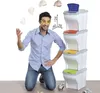 A man is kneeling and juggling crumpled paper balls, with a stack of four colorful recycling bins behind him. Náhľad obrázku produktu
