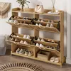 A wooden shoe cabinet with multiple shelves and doors, filled with shoes, placed in a room with a rug and a wall hanging. Voir les images du produit
