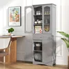 A gray storage cabinet with glass doors and shelves, placed in a room with a table and a plant. Voir les images du produit