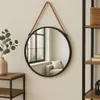A round mirror with a rope hanger is displayed on a wall, next to a shelf and a plant. Produktbild-Vorschau