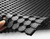A hand is holding and bending a black rubber mat with a hexagonal pattern. Podgląd zdjęcia produktu