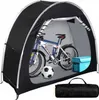 A bicycle stored inside a black tent-like structure, with a soccer ball and a blue storage box nearby. A rolled-up black bag is shown in the foreground. Anteprima dell’immagine prodotto