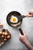 A fried egg being cooked in a pan, with a carton of eggs nearby. Náhled obrázku produktu