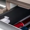 Inside a drawer, showing a white child safety lock and some cylindrical objects. Voir les images du produit