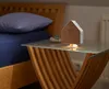 A bedside table with a wooden and white house-shaped sound machine. Produktbild-Vorschau