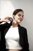 A woman is holding a charging case for earbuds and has one earbud in her ear. Voir les images du produit