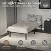 A metal bed frame with bedding and pillows in a bedroom setting, with informational icons at the bottom. Náhled obrázku produktu