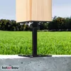 A close-up of a wooden post secured by an adjustable steel post base, set on a concrete curb with a grassy field in the background. Podgląd zdjęcia produktu