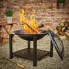 A fire pit with a fire burning, set on a gravel surface next to a brick wall and a stack of firewood. Produktbild-Vorschau