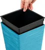 A hand is shown placing a black inner pot into a blue outer planter. Voir les images du produit