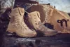 Two beige tactical boots are placed on a rough, textured surface with large rocks in the background. Produktbild-Vorschau