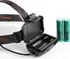 A close-up shot of a black headlamp with its battery compartment open, next to two green batteries. Podgląd zdjęcia produktu