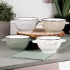 Four ceramic soup bowls are arranged on a countertop with a green napkin. Produktbild-Vorschau