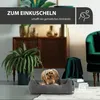 A small dog is resting in a gray corduroy dog bed in a stylish living room setting. Produktbild-Vorschau