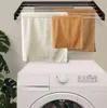 A wall-mounted drying rack with towels hanging on it, positioned above a washing machine. Náhľad obrázku produktu