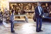 A man holding a chainsaw stands in front of a garage with a boy looking at him. Christmas decorations are visible. Podgląd zdjęcia produktu