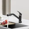 A black kitchen faucet with water running into a sink, next to pomegranates and macarons. Produktbild-Vorschau