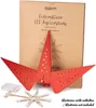 A red LED paper star is displayed in front of its packaging, with the battery pack and LED string shown separately. Náhled obrázku produktu