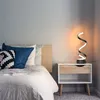 A bedside table with a lamp and pillows next to a bed. Podgląd zdjęcia produktu