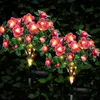 Zwei solarbetriebene rosa Blumenleuchten mit grünen Blättern und warmweißen LEDs, vor dunkelgrünem Blätterhintergrund Anteprima dell’immagine prodotto