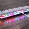A close-up shot of a white mechanical keyboard with RGB lighting, resting on a wooden surface. Produktbild-Vorschau