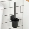 A black toilet brush set mounted on a white tiled wall next to a toilet. Náhled obrázku produktu