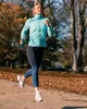 A woman is jogging in a park during autumn, holding a water bottle. Anteprima dell’immagine prodotto