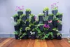 A vertical garden system filled with various plants and flowers, set against a light gray wall and on a wooden floor. Produktbild-Vorschau