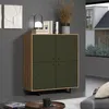 A dark green highboard with a wood-grain frame is placed in a living room setting, next to a window. Podgląd zdjęcia produktu