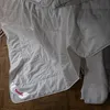 A white comforter is laid out on a wooden floor. Produktbild-Vorschau
