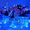 A string of blue LED lights is draped over a bouquet of flowers in a white wooden crate. Produktbild-Vorschau