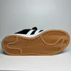 A bottom view of a black and white Adidas sneaker with a gum sole. Voir les images du produit