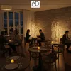 A dimly lit restaurant interior with people dining at tables, decorated with string lights. Podgląd zdjęcia produktu