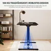 A black standing desk frame is shown in a room with shelves and a plant. Text overlays highlight its load capacity and robust design. Voir les images du produit