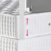 Close-up view of two stacked mattresses with a white support structure and a gray fabric barrier attached to the top mattress. Produktbild-Vorschau