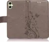 A brown flip case for a smartphone with a floral and butterfly embossed design. Produktbild-Vorschau