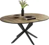 An oval dining table with a wood-grain top and a black, X-shaped base, decorated with a vase of flowers and two books. Náhľad obrázku produktu