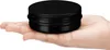 A black aluminum tin is held in a person's palm. Produktbild-Vorschau