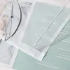 Close-up of a sheer curtain with embroidered details, layered over magazine pages. Produktbild-Vorschau