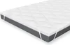 A white mattress topper with a diamond-stitched pattern is shown on top of a gray mattress. White elastic straps are visible on the sides, designed to secure the topper to the mattress. Produktbild-Vorschau