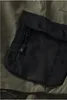 A close-up view of a black zippered pocket on an olive green garment. Produktbild-Vorschau