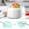 A yogurt parfait with strawberries and granola in a glass jar, with a close-up of yogurt on a spoon. Produktbild-Vorschau