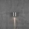 A silver cylindrical wall light mounted on a textured gray concrete wall, casting a downward light. Anteprima dell’immagine prodotto
