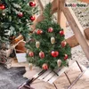 Two decorated Christmas trees, one small on a sled and one larger, are displayed outdoors on a wooden surface. Produktbild-Vorschau