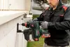 A man is using a Metabo hammer drill to drill into a wall. Voir les images du produit