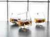 Three whiskey glasses with whiskey and ice cubes on a dark surface, with a blurred background of white glass blocks. Podgląd zdjęcia produktu