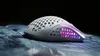 A white gaming mouse with RGB lighting is shown on a textured surface. Podgląd zdjęcia produktu