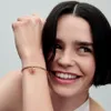 A woman smiles as she shows off a butterfly charm bracelet on her wrist. Anteprima dell’immagine prodotto